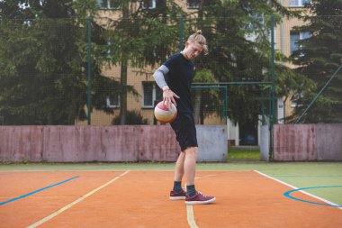 Basketbolcu, sahanın dışında oynanan sıradan bir maçta topu kontrol ediyor ve top sürüyor, odak noktasına eğiliyor. Saray ağaçlar ve doğa ile çevrili. Huzurlu ve atletik bir atmosfer sağlıyor..