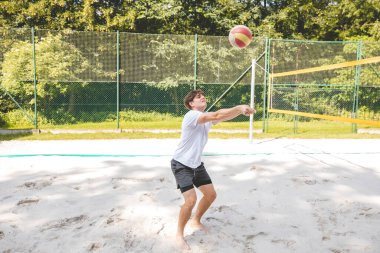Voleybol oyuncusu, top sahasında pas veriyor, hassas top kontrolü ve tekniğine odaklanıyor. Yoğun bir plaj voleybolu maçında yakalandı..