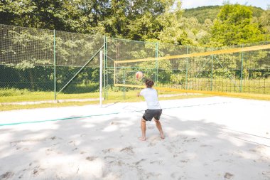 Voleybol oyuncusu, top sahasında pas veriyor, hassas top kontrolü ve tekniğine odaklanıyor. Yoğun bir plaj voleybolu maçında yakalandı..