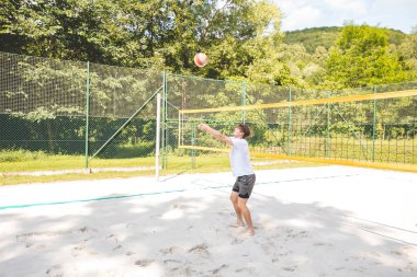 Voleybol oyuncusu, top sahasında pas veriyor, hassas top kontrolü ve tekniğine odaklanıyor. Yoğun bir plaj voleybolu maçında yakalandı..