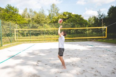 Voleybol oyuncusu topu bir kumsal voleybolu maçında bir sonraki oyuna hazırlıyor. Eylem oyunda kontrol ve kesinliği vurgular.