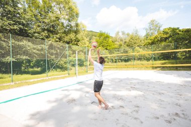 Voleybol oyuncusu topu bir kumsal voleybolu maçında bir sonraki oyuna hazırlıyor. Eylem oyunda kontrol ve kesinliği vurgular.