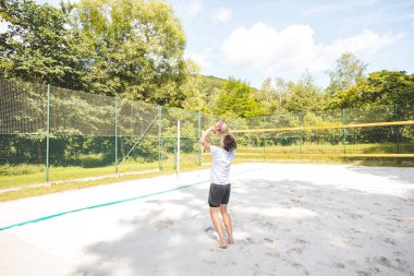 Voleybol oyuncusu topu bir kumsal voleybolu maçında bir sonraki oyuna hazırlıyor. Eylem oyunda kontrol ve kesinliği vurgular.
