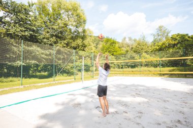 Voleybol oyuncusu topu bir kumsal voleybolu maçında bir sonraki oyuna hazırlıyor. Eylem oyunda kontrol ve kesinliği vurgular.