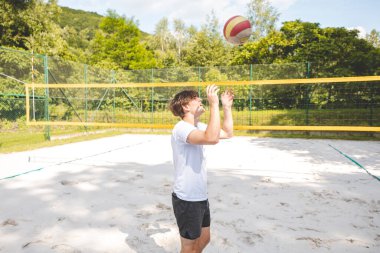 Voleybol oyuncusu, bir top tutuyor ve bir sonraki oyuna hazırlanıyor. Açık deniz voleybolu maçında..