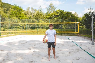 Voleybol oyuncusu, bir top tutuyor ve bir sonraki oyuna hazırlanıyor. Açık deniz voleybolu maçında..