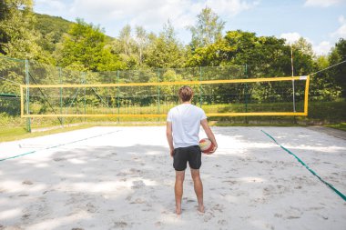 Voleybol oyuncusu, bir top tutuyor ve bir sonraki oyuna hazırlanıyor. Açık deniz voleybolu maçında..