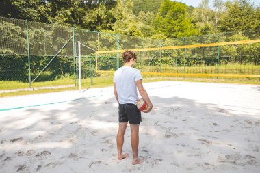 Voleybol oyuncusu, bir top tutuyor ve bir sonraki oyuna hazırlanıyor. Açık deniz voleybolu maçında..