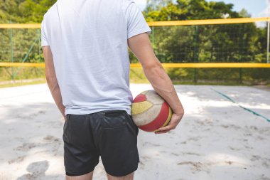 Voleybol oyuncusu, bir top tutuyor ve bir sonraki oyuna hazırlanıyor. Açık deniz voleybolu maçında..