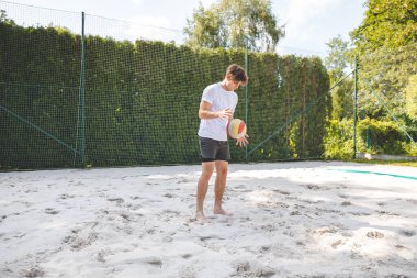Voleybol oyuncusu, bir top tutuyor ve bir sonraki oyuna hazırlanıyor. Açık deniz voleybolu maçında..