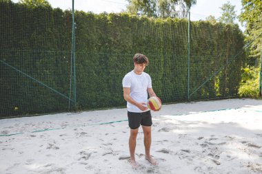 Voleybol oyuncusu, bir top tutuyor ve bir sonraki oyuna hazırlanıyor. Açık deniz voleybolu maçında..