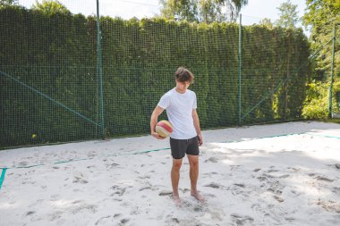 Voleybol oyuncusu, bir top tutuyor ve bir sonraki oyuna hazırlanıyor. Açık deniz voleybolu maçında..
