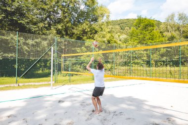 Voleybol oyuncusu topu bir kumsal voleybolu maçında bir sonraki oyuna hazırlıyor. Eylem oyunda kontrol ve kesinliği vurgular.