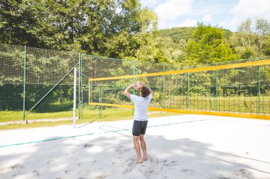 Voleybol oyuncusu topu bir kumsal voleybolu maçında bir sonraki oyuna hazırlıyor. Eylem oyunda kontrol ve kesinliği vurgular.