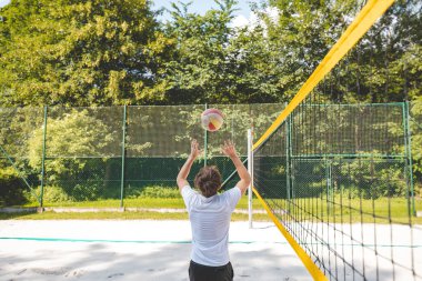 Voleybol oyuncusu topu bir kumsal voleybolu maçında bir sonraki oyuna hazırlıyor. Eylem oyunda kontrol ve kesinliği vurgular.