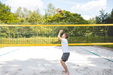 Voleybol oyuncusu topu bir kumsal voleybolu maçında bir sonraki oyuna hazırlıyor. Eylem oyunda kontrol ve kesinliği vurgular.
