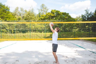 Voleybol oyuncusu topu bir kumsal voleybolu maçında bir sonraki oyuna hazırlıyor. Eylem oyunda kontrol ve kesinliği vurgular.