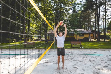 Voleybol oyuncusu topu bir kumsal voleybolu maçında bir sonraki oyuna hazırlıyor. Eylem oyunda kontrol ve kesinliği vurgular.