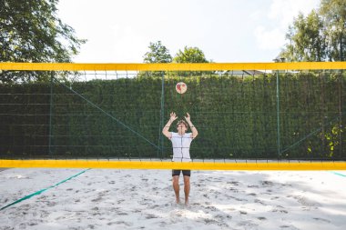 Voleybol oyuncusu topu bir kumsal voleybolu maçında bir sonraki oyuna hazırlıyor. Eylem oyunda kontrol ve kesinliği vurgular.
