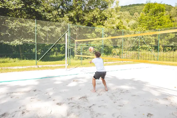 Voleybol oyuncusu, top sahasında pas veriyor, hassas top kontrolü ve tekniğine odaklanıyor. Yoğun bir plaj voleybolu maçında yakalandı..
