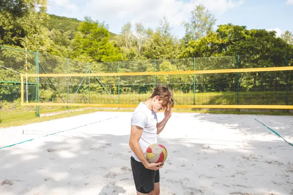Voleybol oyuncusu, bir top tutuyor ve bir sonraki oyuna hazırlanıyor. Açık deniz voleybolu maçında..