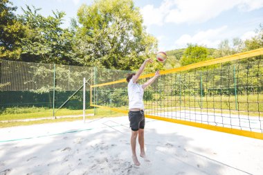 Voleybol oyuncusu topu bir kumsal voleybolu maçında bir sonraki oyuna hazırlıyor. Eylem oyunda kontrol ve kesinliği vurgular.