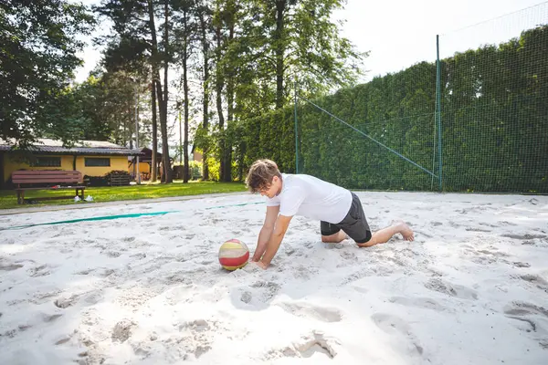 Voleybol oyuncusu, voleybol topunu kumlu bir sahada kazıyor. Sahil voleybolunun yoğunluğunu ve odak noktasını açık hava ortamında yakalamak.