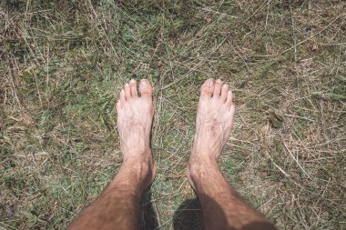 Çıplak ayaklar güneşli, kuru çimenlerin üzerinde duruyor, Çek Cumhuriyeti 'nin Beskydy Dağları' ndaki sakin bir anda doğayla, basitlikle ve topraklanmayla olan bağlantıyı simgeliyor..