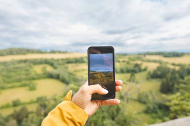 Akıllı bir telefonla Beskydy Dağları 'ndaki yuvarlanan tarlaların ve yeşil ormanların resimli manzarasını yakalar ve modern teknolojiyi doğal güzellikle harmanlar..