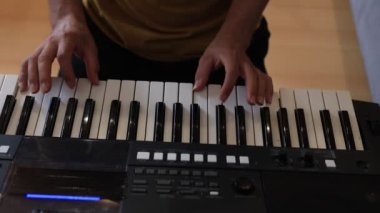 Müzisyen elleri rahatça dijital bir klavyenin üzerinde süzülerek rahat bir ev ortamında beceri ve hassasiyet sergiliyor. Video yaratıcılığı ve müzikal tutkuyu vurguluyor
