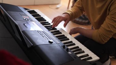 Müzisyen elleri rahatça dijital bir klavyenin üzerinde süzülerek rahat bir ev ortamında beceri ve hassasiyet sergiliyor. Video yaratıcılığı ve müzikal tutkuyu vurguluyor