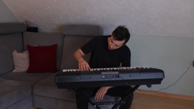 Odaklanmış müzisyen ince melodileri ve rahat bir oturma odasında elektronik bir klavye çalıyor. Sahne yaratıcılığı, kararlılığı ve müziğe olan tutkuyu vurguluyor.