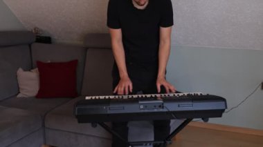 Odaklanmış müzisyen ince melodileri ve rahat bir oturma odasında elektronik bir klavye çalıyor. Sahne yaratıcılığı, kararlılığı ve müziğe olan tutkuyu vurguluyor.