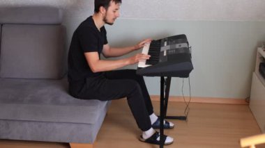 Odaklanmış müzisyen ince melodileri ve rahat bir oturma odasında elektronik bir klavye çalıyor. Sahne yaratıcılığı, kararlılığı ve müziğe olan tutkuyu vurguluyor.