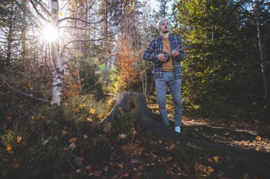 Genç adam güneşli bir ormanda ağaç kütüğünde oturur ve ukulele çalar. Sonbahar renkleri ve ağaçların arasından süzülen yumuşak güneş ışığıyla çevrelenmiş doğa ve müzikle barışçıl bir bağ kuruyor..