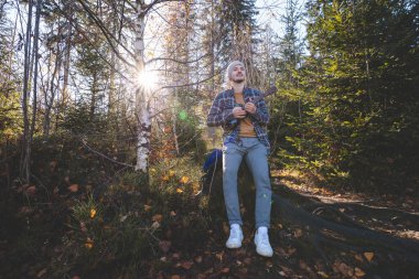 Genç adam güneşli bir ormanda ağaç kütüğünde oturur ve ukulele çalar. Sonbahar renkleri ve ağaçların arasından süzülen yumuşak güneş ışığıyla çevrelenmiş doğa ve müzikle barışçıl bir bağ kuruyor..