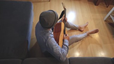 Müzisyen sıcak bir oturma odasında sıcak bir kanepede oturup akustik gitar tıngırdatıyor. Video, onların rahat duruşlarını ve müziğin rahatlatıcı tonlarını yakalıyor.