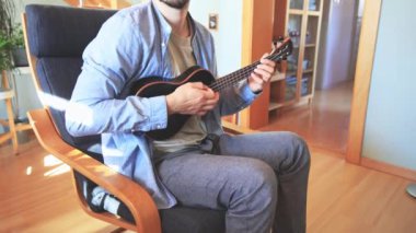 Siyah bir ukulele üzerinde yeni melodiler ve tonlarla yapılan bir müzik deneyi, evlerinin konforu altında ukulele çalma sevincine tamamen dalmış yeni bir şarkı besteledi. 4K video