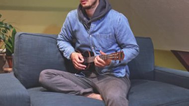Siyah bir ukulele üzerinde yeni melodiler ve tonlarla yapılan bir müzik deneyi, evlerinin konforu altında ukulele çalma sevincine tamamen dalmış yeni bir şarkı besteledi. 4K video