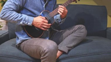 Siyah bir ukulele üzerinde yeni melodiler ve tonlarla yapılan bir müzik deneyi, evlerinin konforu altında ukulele çalma sevincine tamamen dalmış yeni bir şarkı besteledi. 4K video