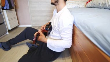 Siyah bir ukulele üzerinde yeni melodiler ve tonlarla yapılan bir müzik deneyi, evlerinin konforu altında ukulele çalma sevincine tamamen dalmış yeni bir şarkı besteledi. 4K video