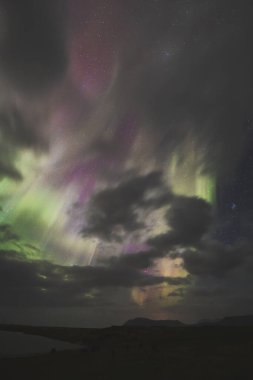 Aurora Borealis, kuzey ışıkları, Snaefellsnes yarımadası üzerinde, Batı İzlanda. Parlak yeşil, mor gökyüzü, dönen ışıklar, yıldızlı gece, yansıyan su, dingin doğa harikası.