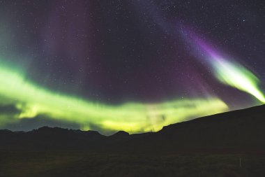 Kuzey ışıkları, Aurora borealis, Batı İzlanda 'daki Snaefellsnes yarımadasındaki kayalık volkanik dağların üzerinde çeşitli renklerde gece gökyüzü boyunca uzanır. Bir gece masalı.
