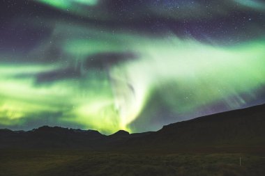 Kuzey ışıkları, Aurora borealis, Batı İzlanda 'daki Snaefellsnes yarımadasındaki kayalık volkanik dağların üzerinde çeşitli renklerde gece gökyüzü boyunca uzanır. Bir gece masalı.