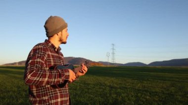 Tutkulu 26 yaşındaki müzisyen günbatımında gitar çalarak açık havada eğleniyor. Doğada olmak. Modern halk tarzında doğa ve müziğe duyulan sevginin bir karışımı. 4k video