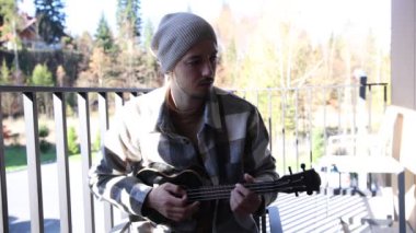 Tutkulu 26 yaşındaki müzisyen günbatımında gitar çalarak açık havada eğleniyor. Doğada olmak. Modern halk tarzında doğa ve müziğe duyulan sevginin bir karışımı. 4k video