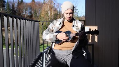 Tutkulu 26 yaşındaki müzisyen günbatımında gitar çalarak açık havada eğleniyor. Doğada olmak. Modern halk tarzında doğa ve müziğe duyulan sevginin bir karışımı. 4k video