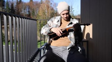 Tutkulu 26 yaşındaki müzisyen günbatımında gitar çalarak açık havada eğleniyor. Doğada olmak. Modern halk tarzında doğa ve müziğe duyulan sevginin bir karışımı. 4k video