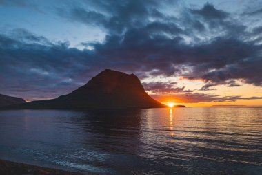 Güneş batarken İzlanda 'daki Snaefellsnes yarımadasında Kirkjufell Dağı. İkonik zirve, akşam gökyüzünün canlı renkleriyle çevrili sakin sulara yansıyor..