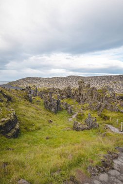 Djupalonssandur on the Snaefellsnes Peninsula, Iceland, featuring dramatic volcanic rock formations, a black pebble beach, and distant mountains. clipart